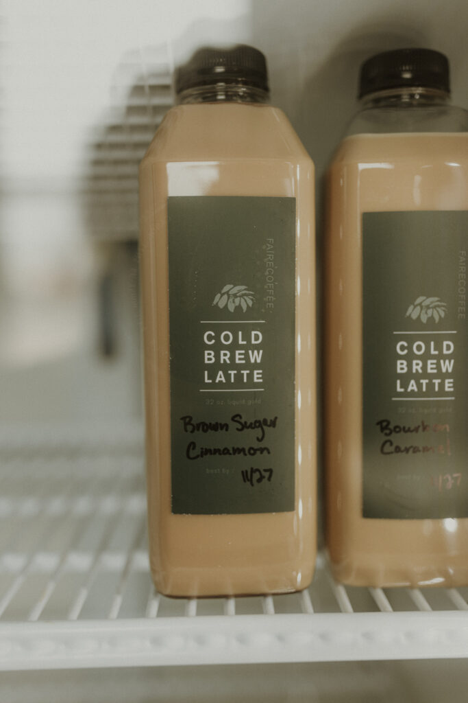 Close-up of bottled cold brew lattes from Faire Coffee in Eureka, IL, featuring flavors like Brown Sugar Cinnamon and Bourbon Caramel, neatly displayed on a refrigerator shelf.